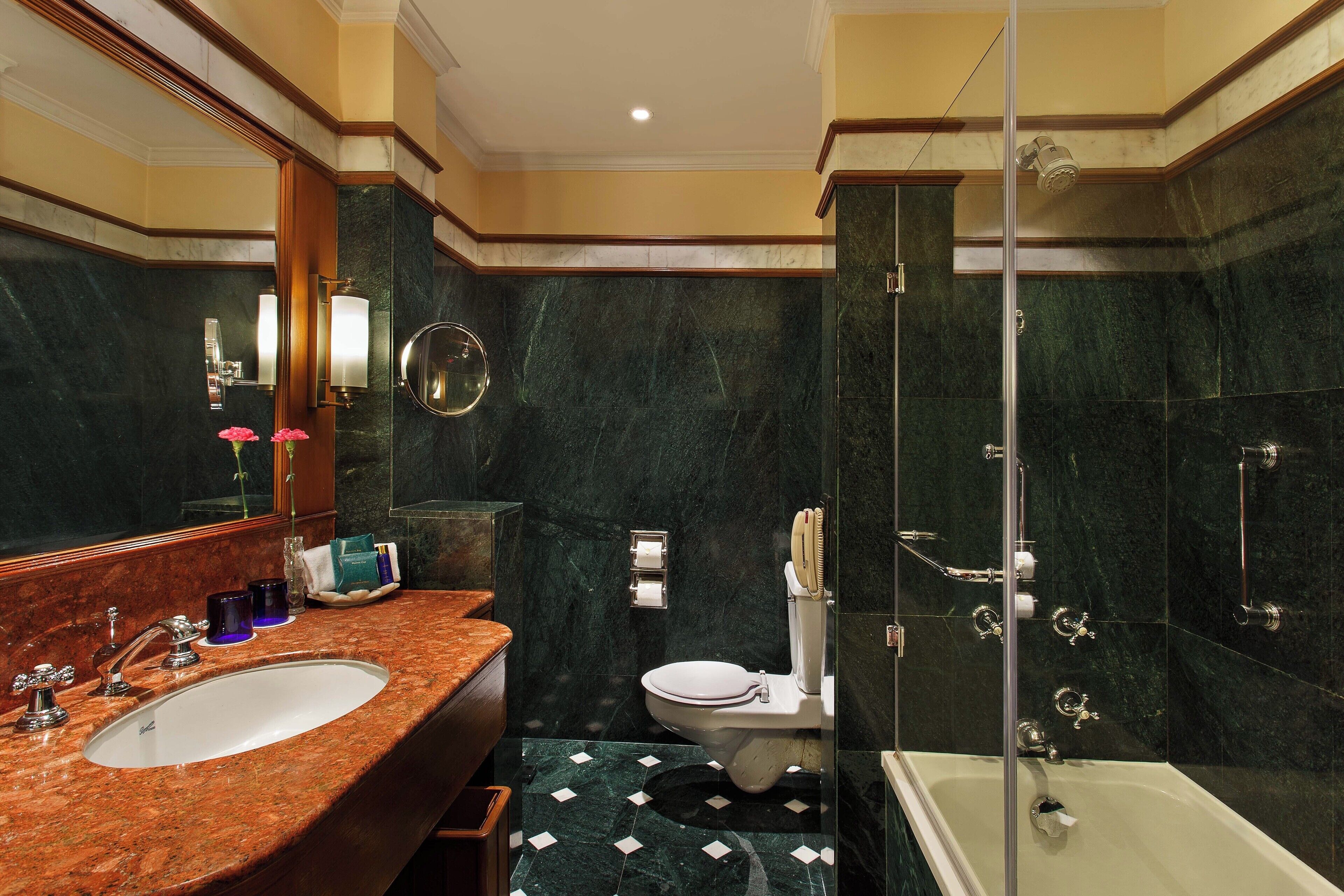 Une salle de bain avec un lavabo, des toilettes et une baignoire, le tout en marbre.