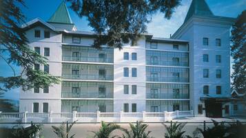 A multi-story building with a symmetrical facade, large windows, and a white exterior.