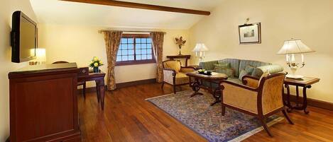 A cozy living room with a wooden floor, a sofa set, a coffee table, and a TV.