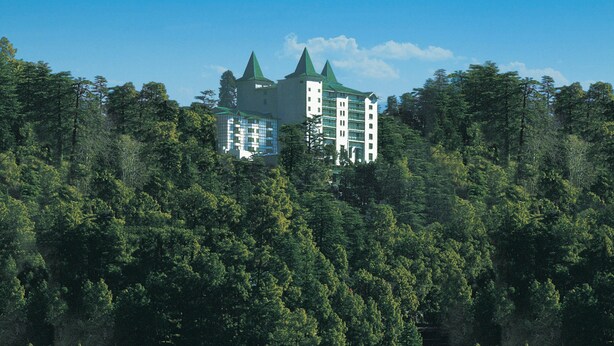 Un edificio con aspecto de castillo rodeado de un bosque frondoso.