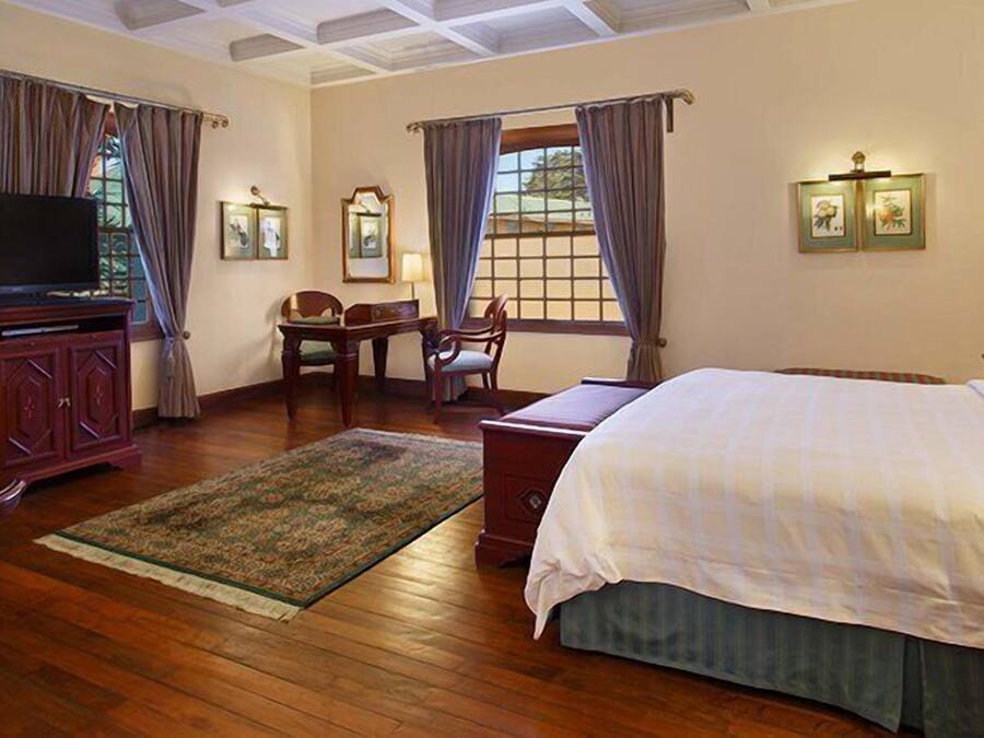 Una habitación de hotel con una cama, televisión, escritorio y una silla.