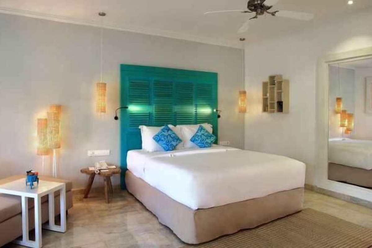 A hotel room with a bed, bedside tables, a ceiling fan, and a large window.