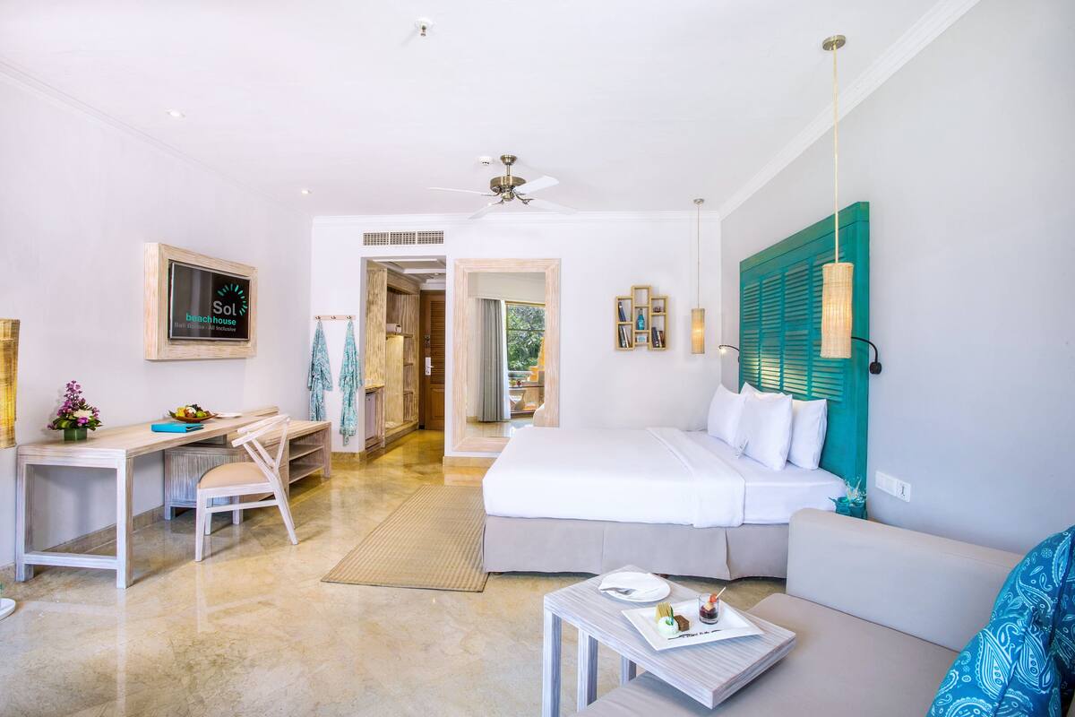 A modern hotel room with a bed, desk, and seating area.