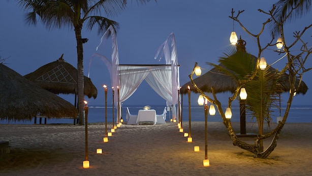 Decoración para una boda en la playa, con una carpa, mesas y velas.