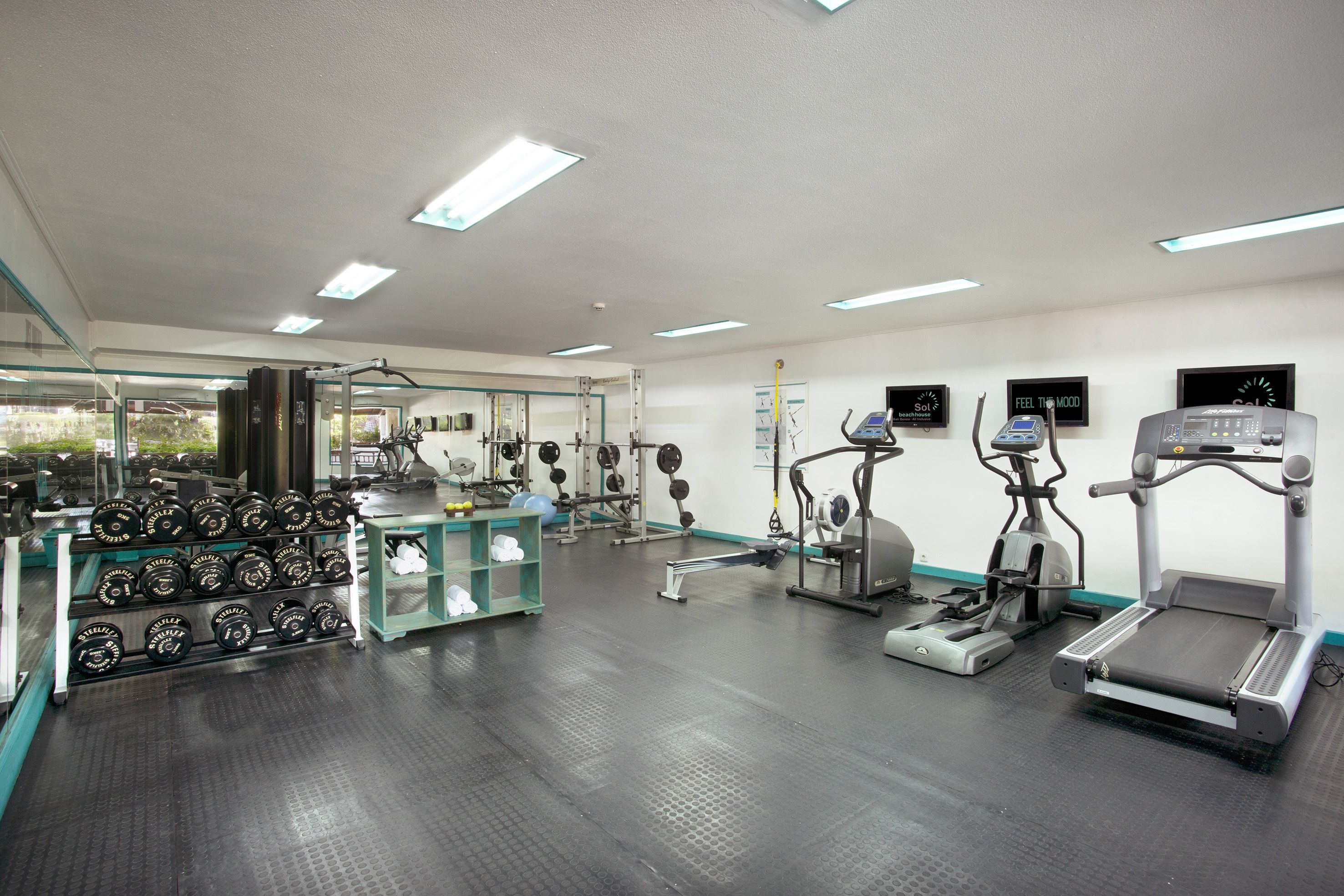 A gym with treadmills, elliptical machines, and weight racks.