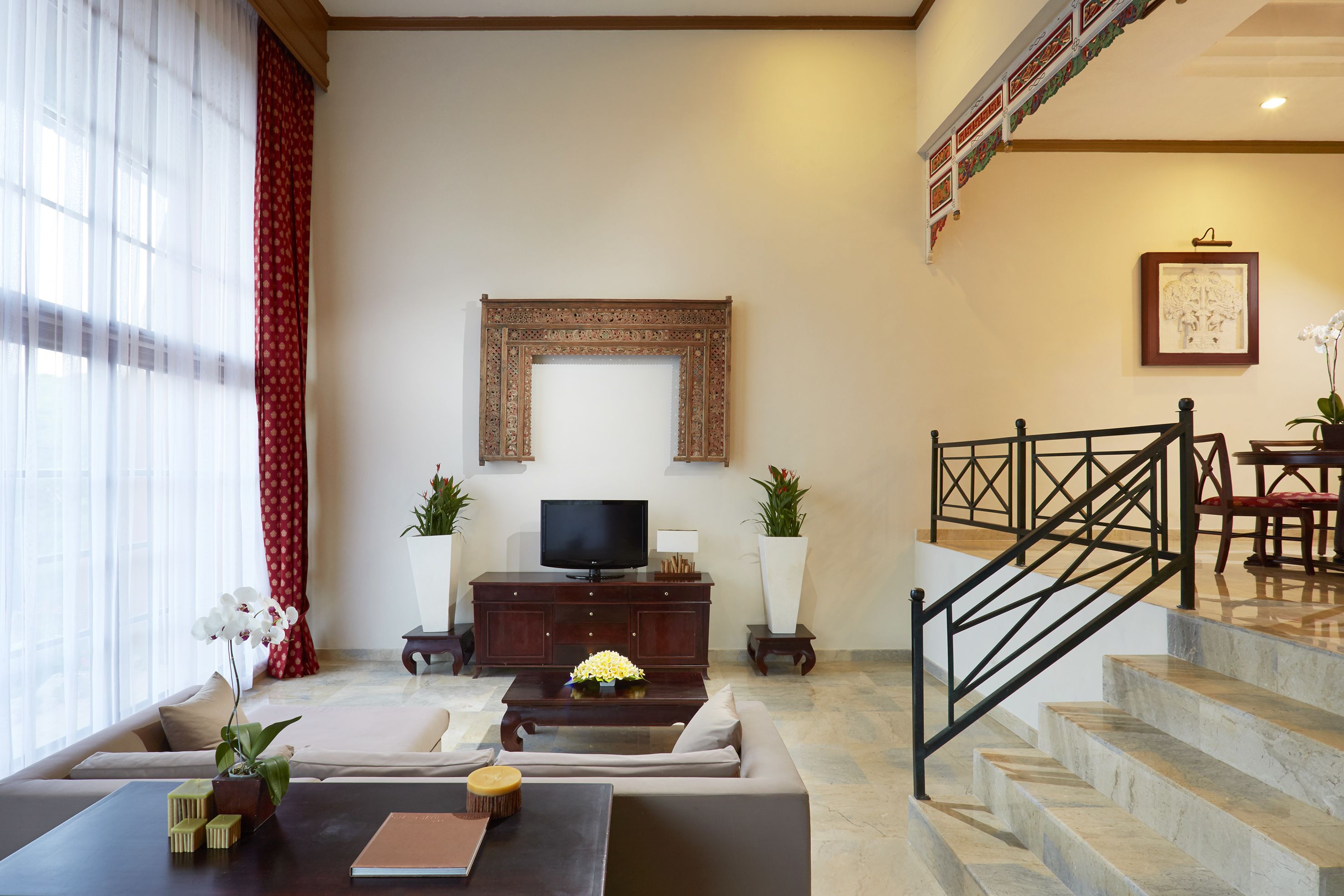 A living room with a sofa, coffee table, TV, and decorative plants.