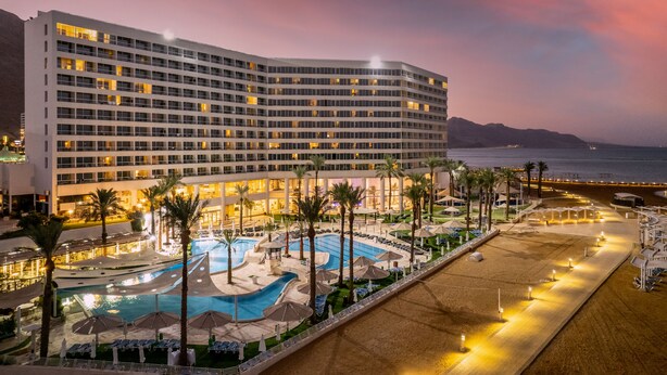 Un hotel con un amplio espacio de piscina, varias piscinas y una playa con sombrillas.