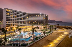 A hotel with a large pool area, multiple swimming pools, and a beach with umbrellas. - Vert Dead Sea By AFI Hotels (Tamar)
