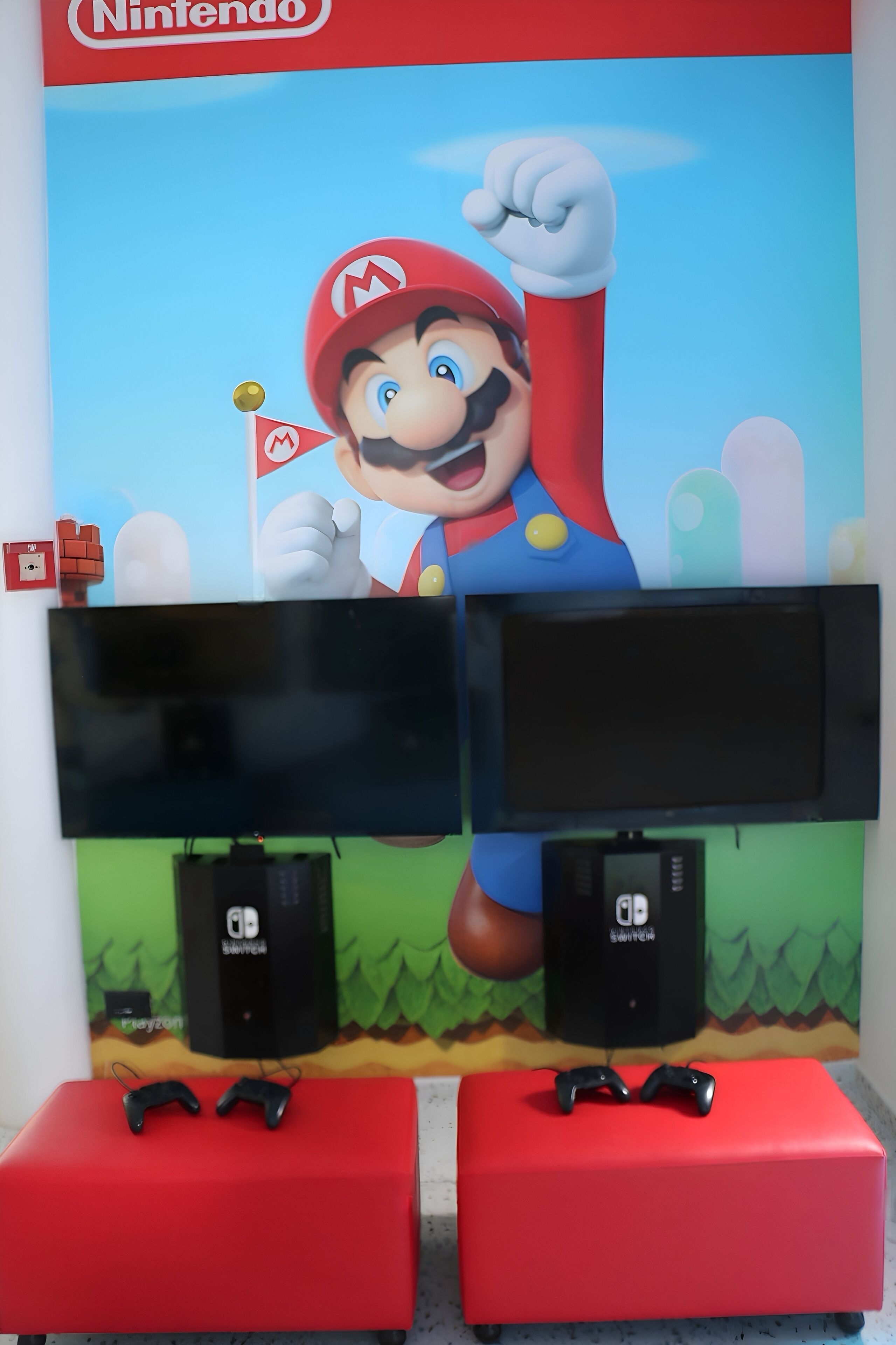 Un mur décoré sur le thème de Nintendo, avec deux téléviseurs et deux haut-parleurs.
