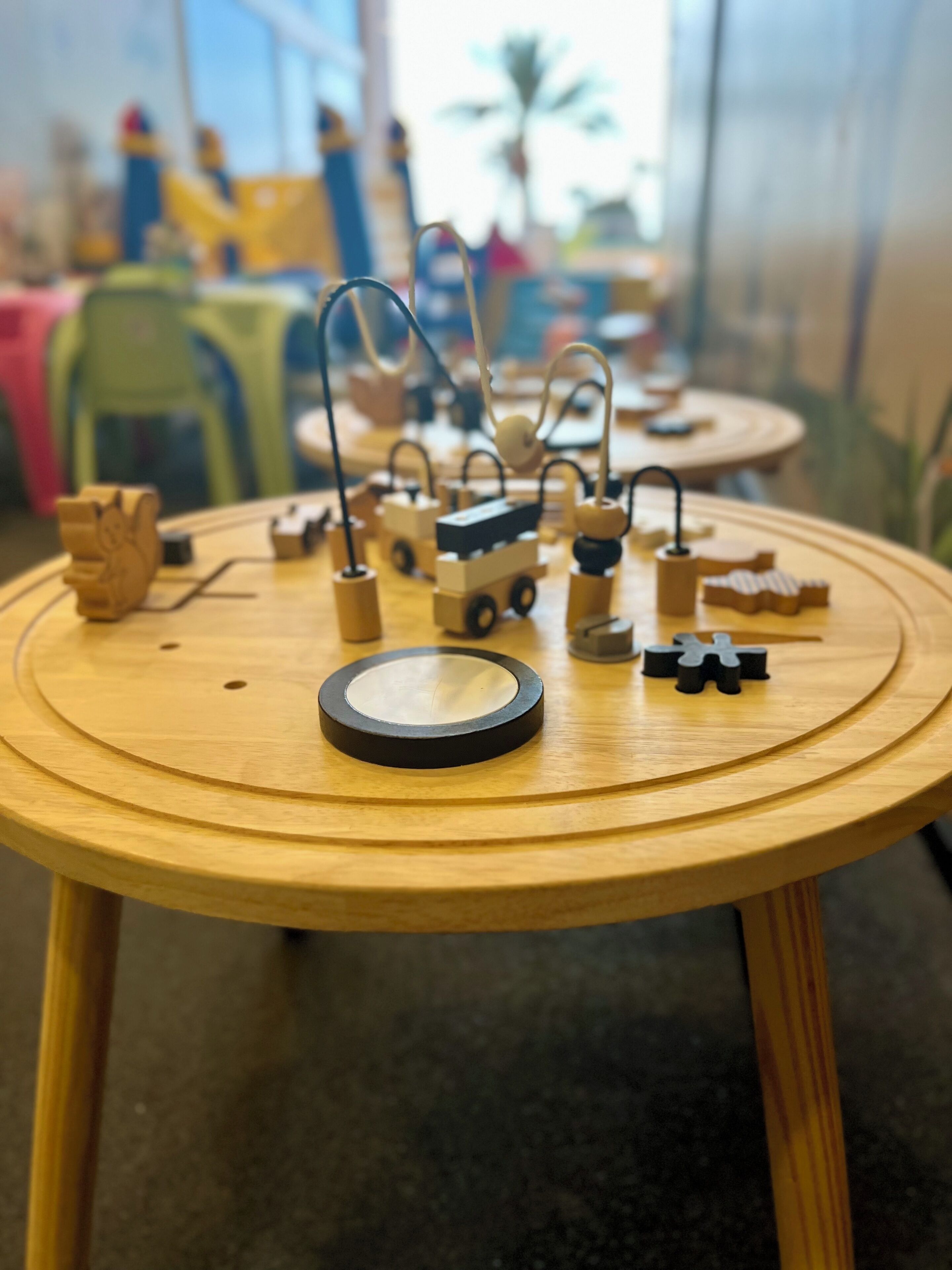 Una mesa de madera con un tren de juguete y varias figuras de madera.