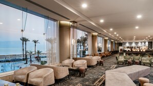 Vestíbulo de hotel con vista a la piscina, zonas de estar y un bar.