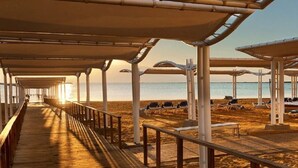 Un paseo marítimo de madera que lleva a sombrillas y sillas de playa.