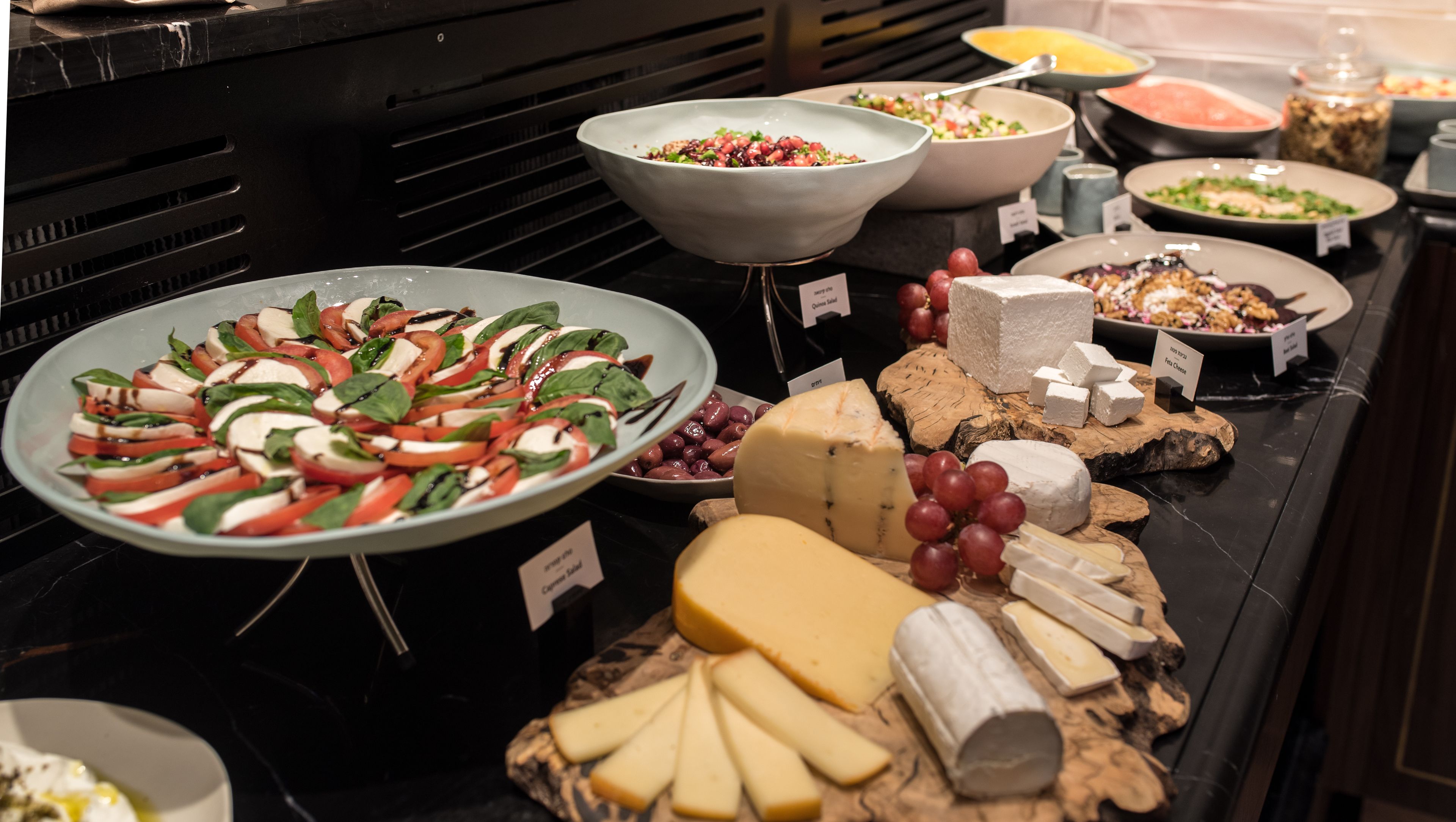 Un buffet proposant une variété de fromages, d’olives et une salade.