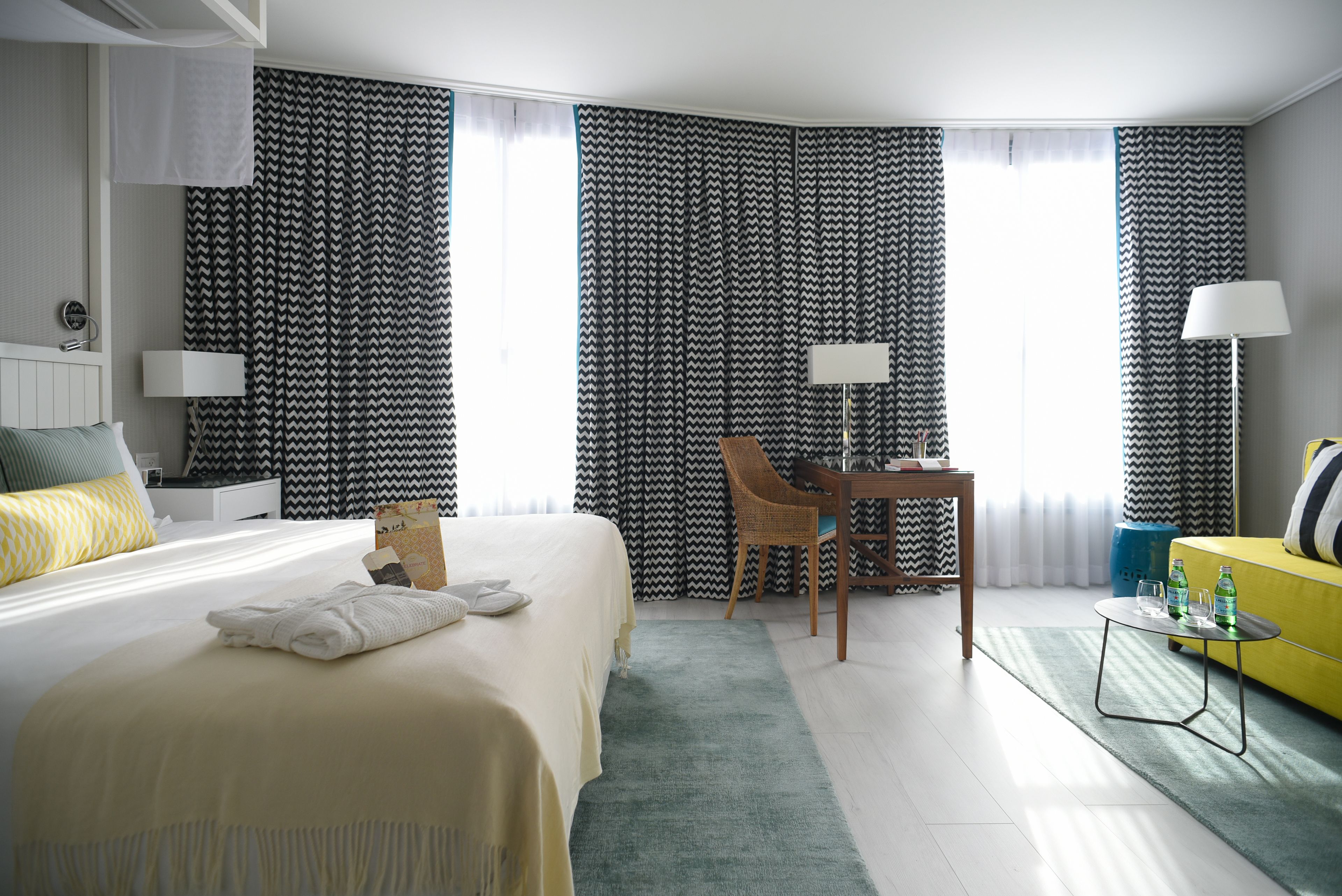 Ein Hotelzimmer mit Bett, Schreibtisch, Stuhl, Lampe und Sofa.