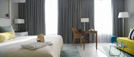 Una habitación de hotel con cama, escritorio, silla, lámpara y sofá.