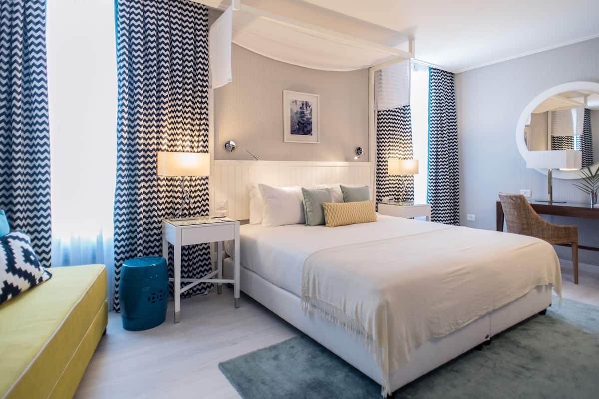 Une chambre d’hôtel moderne, dotée d’un grand lit, de tables de chevet, d’un bureau et d’une chaise.