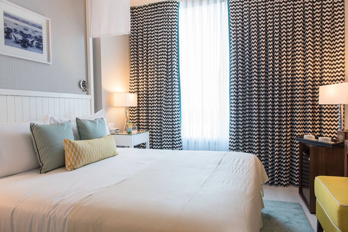 Une chambre d’hôtel avec un grand lit, deux tables de chevet, un bureau et une chaise.