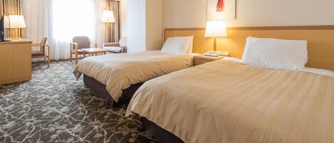 Una habitación de hotel con dos camas, un escritorio, una silla y una lámpara.