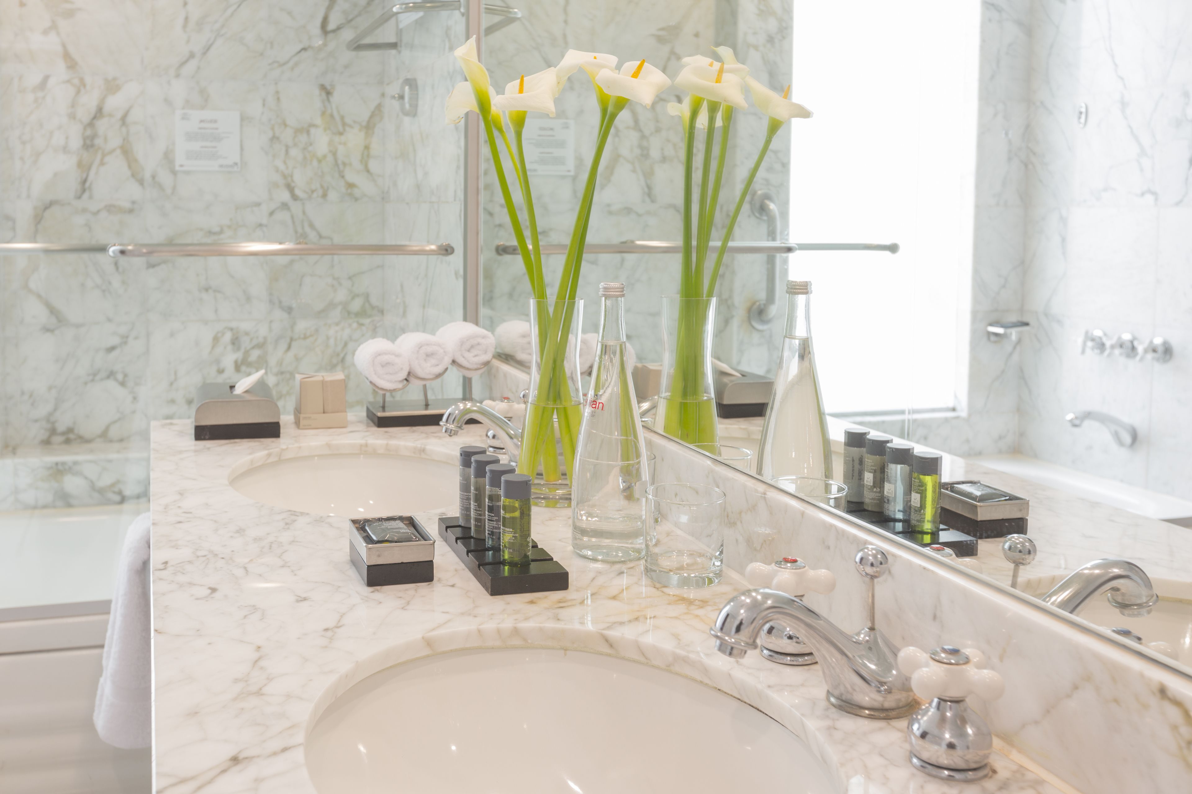 A bathroom with two sinks, a large mirror, and toiletries on the counter.