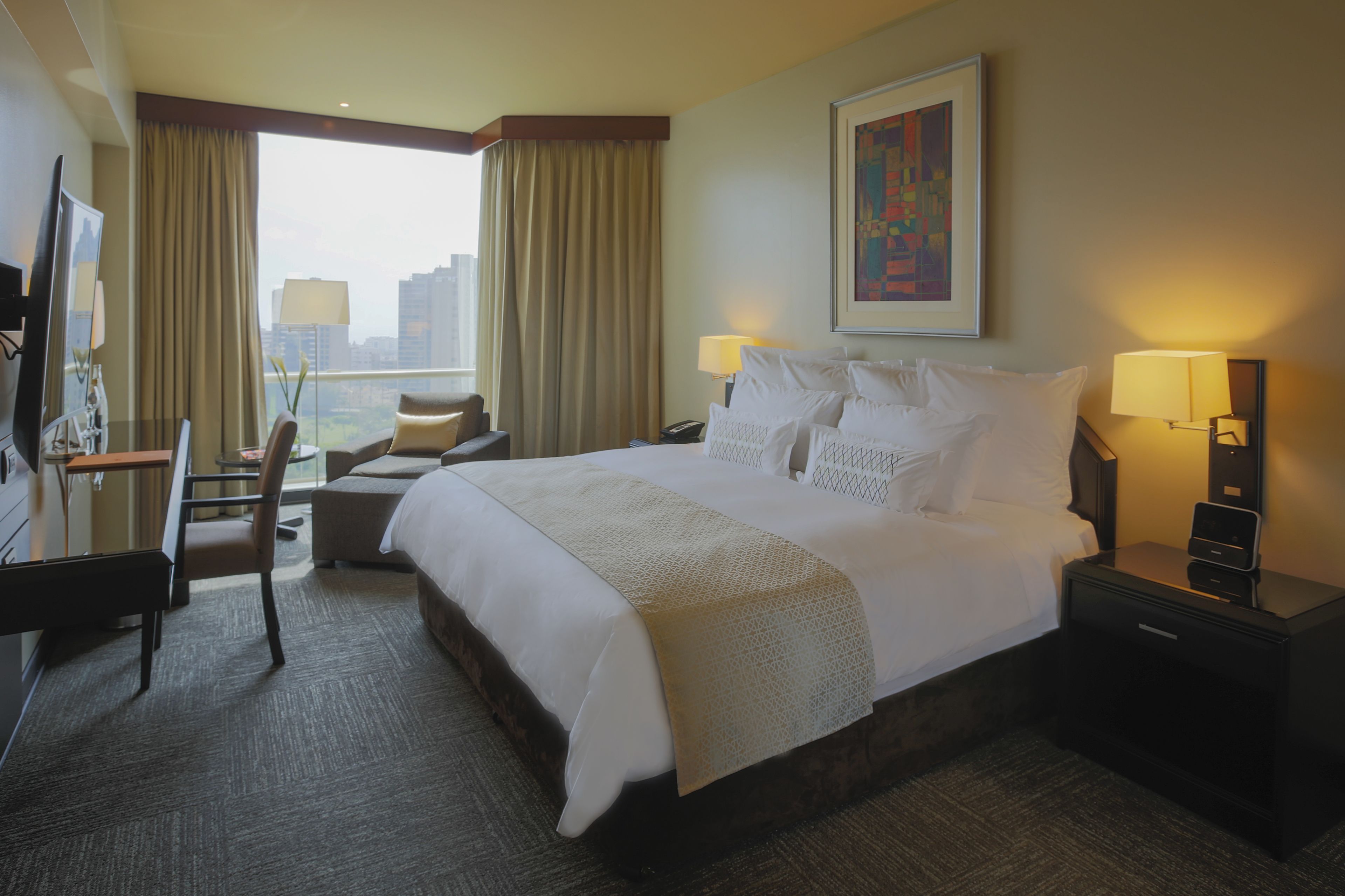 A hotel room with a large bed, a desk, a chair, and a TV.