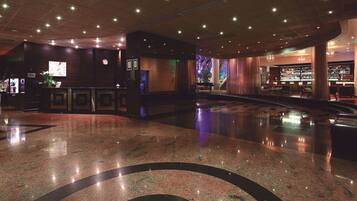 A lobby with a polished marble floor, a reception desk, and a bar area with a visible staircase.