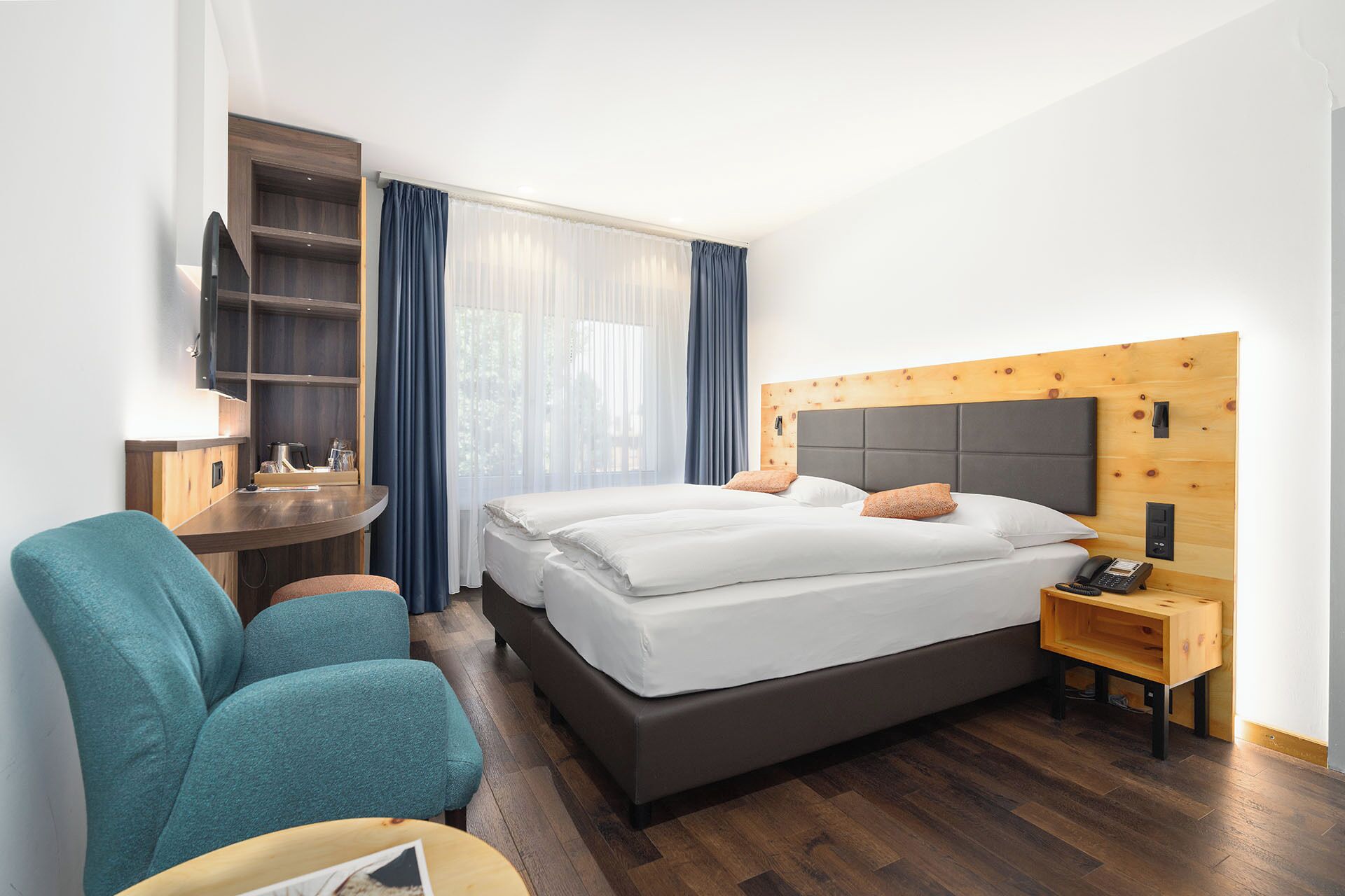 A hotel room with a bed, a desk, a chair, and a nightstand.