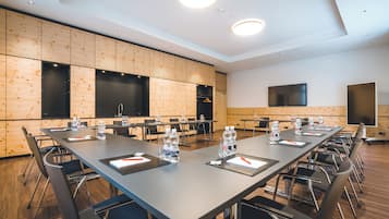 Une salle de conférence avec une longue table, des chaises, des bouteilles d’eau et un téléviseur à écran plat.