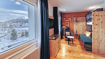 A cozy room with a large window, wooden walls, a blue chair, and a small table.