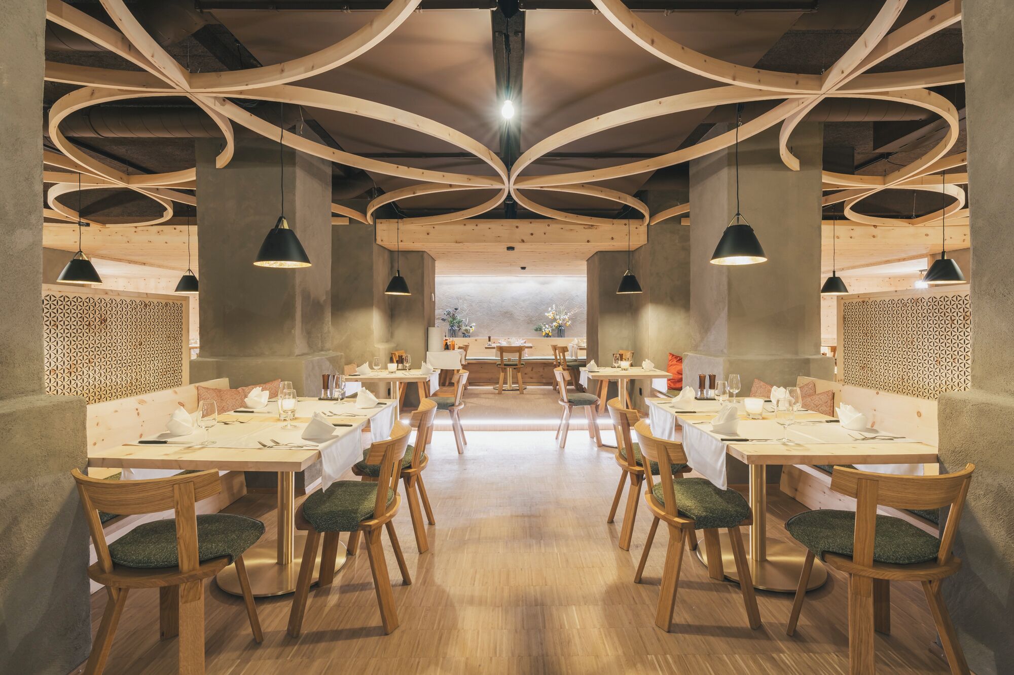 Ein Restaurant mit modernem Interieur, das Holztische und -stühle sowie ein einzigartiges Decken­design bietet.
