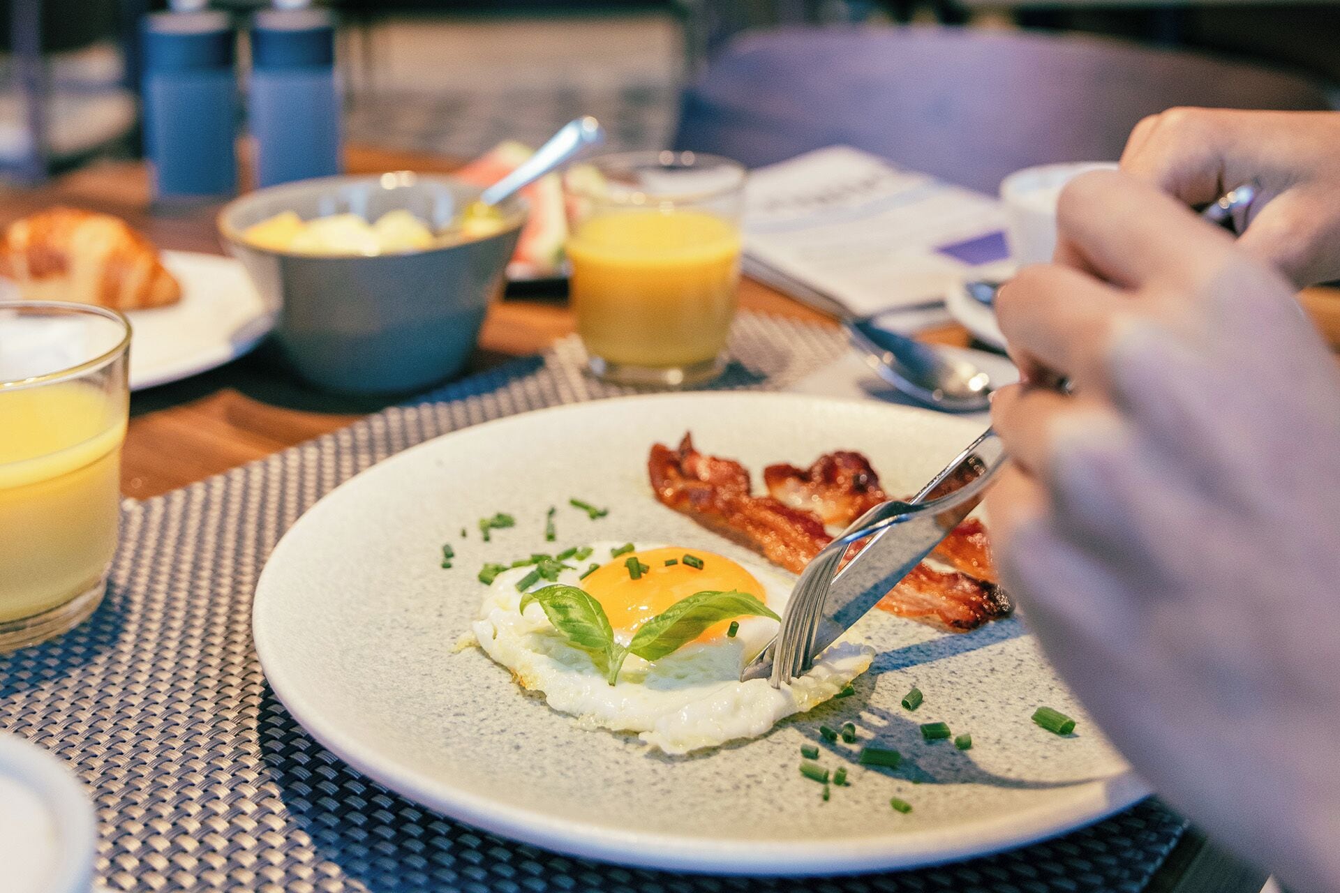 A breakfast setting with a plate of eggs, bacon, and a glass of orange juice.