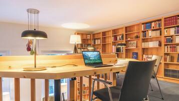 A study area with a desk, laptop, chair, and bookshelves filled with books.