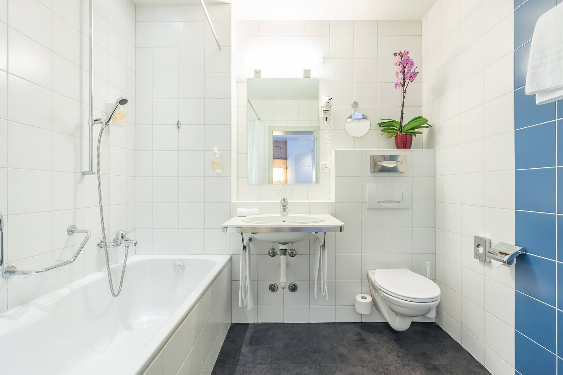 A modern bathroom with a bathtub, sink, toilet, and a mirror.