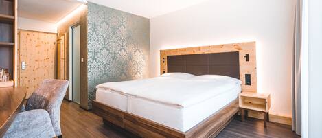 Una habitación de hotel moderna con una cama de madera, un escritorio pequeño y una silla roja.