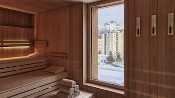 Un sauna avec des bancs en bois et une grande fenêtre donnant sur un paysage enneigé.
