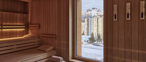 Una sauna con bancos de madera y un amplio ventanal con vistas a un paisaje nevado.