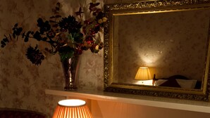 Ein gemütlicher Raum mit Holztisch, Lampe, Spiegel und Kamin.