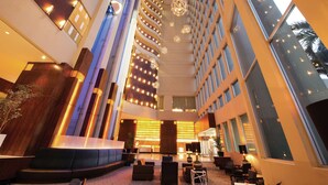 A spacious lobby with a modern design, featuring a central seating area, large windows, and a high ceiling with decorative lighting. - Hilton Colon Guayaquil (Guayaquil)