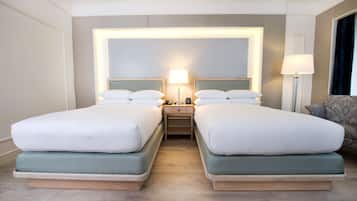 Une chambre d’hôtel avec deux lits, une table de chevet avec une lampe et une chaise.