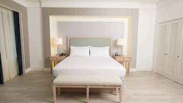 A neatly arranged hotel room with a large bed, bedside tables, a bench, and a wardrobe.