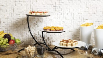 Une table de buffet avec divers plats et un saladier de fruits.