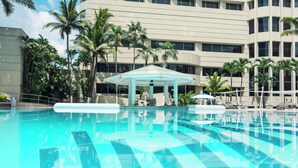 A swimming pool with a clear blue water surface, surrounded by palm trees and a building with multiple windows. - Hilton Colon Guayaquil (Guayaquil)