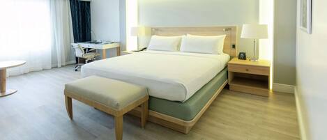 A modern hotel room with a large bed, bedside tables, a desk, and a chair.