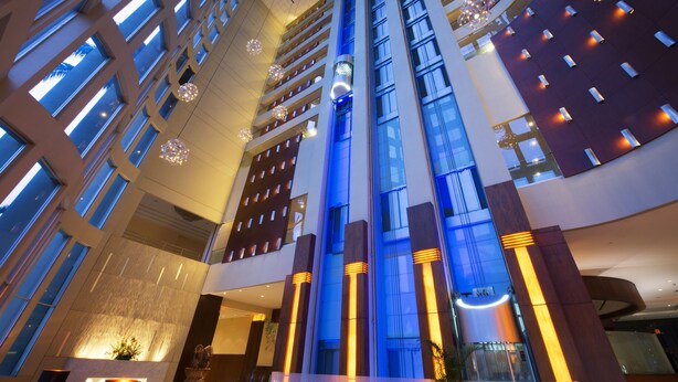 A high-rise hotel interior with multiple floors, large windows, and modern lighting fixtures. - Hilton Colon Guayaquil (Guayaquil)