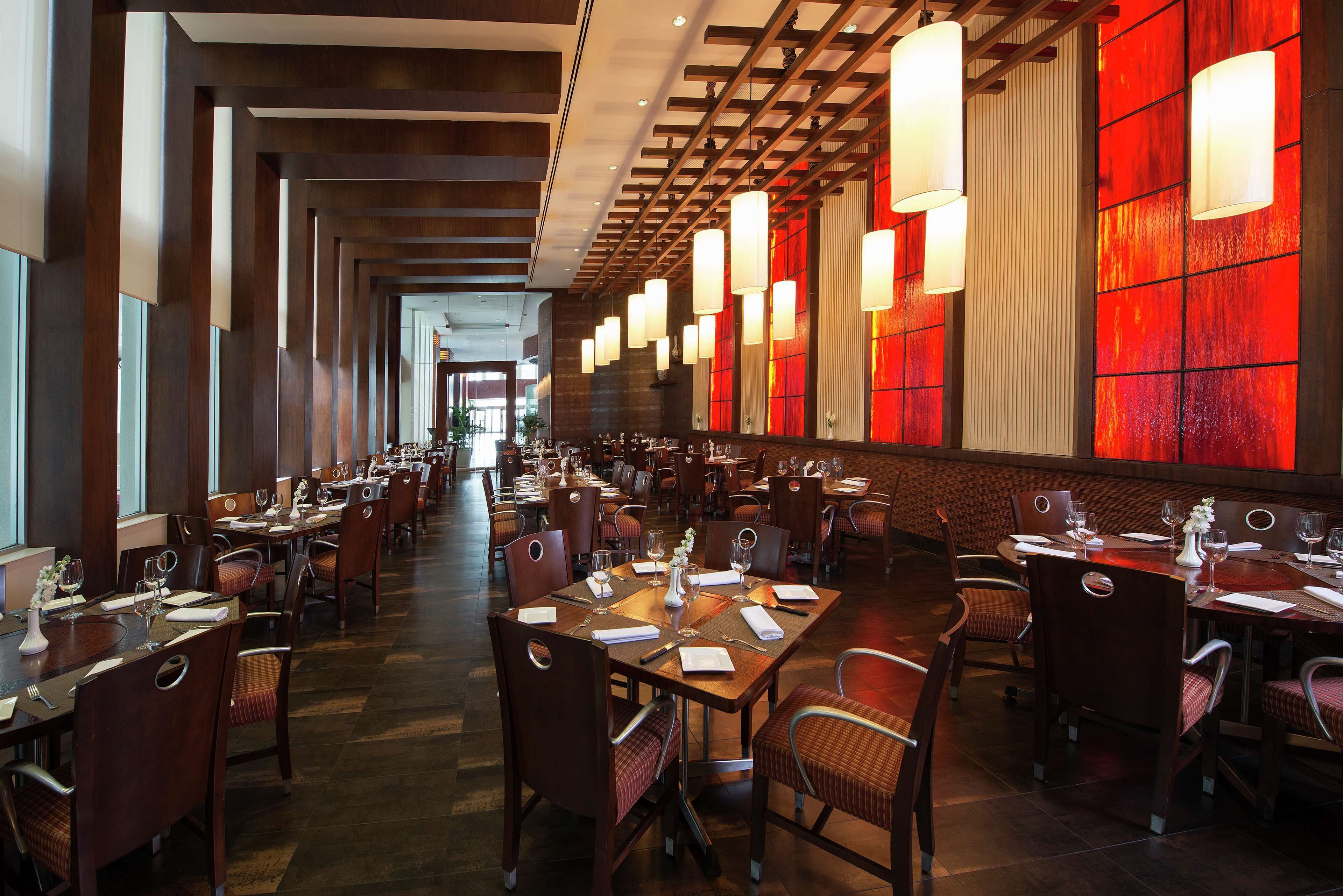A spacious restaurant with long tables and chairs, warm lighting, and a modern interior design.