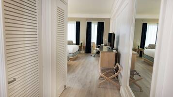 A hotel room with a bed, desk, chair, and a mirror.