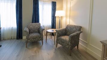 Una habitación con dos sillones estampados, una mesita redonda pequeña y una lámpara de pie.
