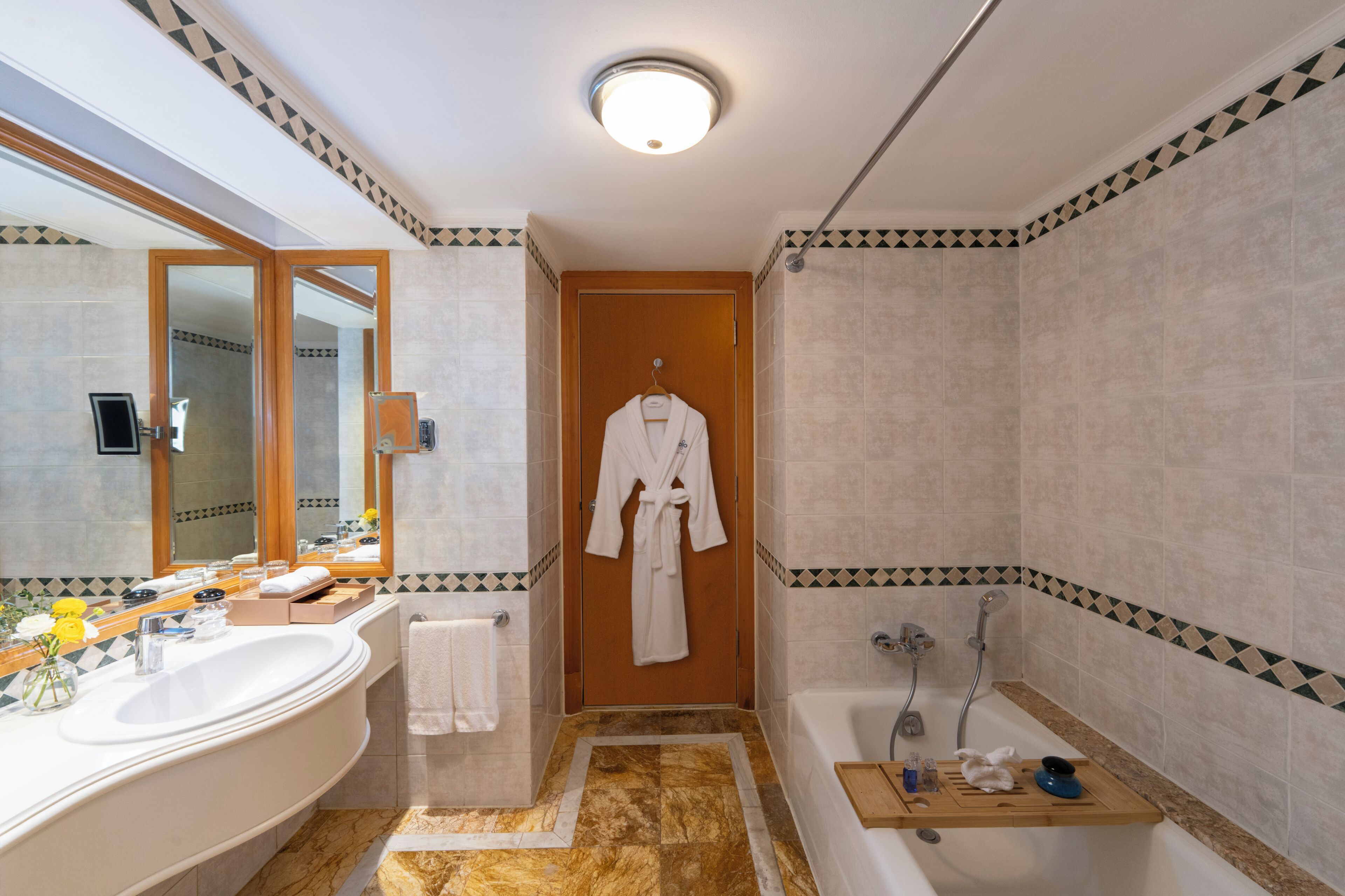 A bathroom with a large bathtub, a separate shower area, a vanity with a mirror, and a robe hanging on the wall.
