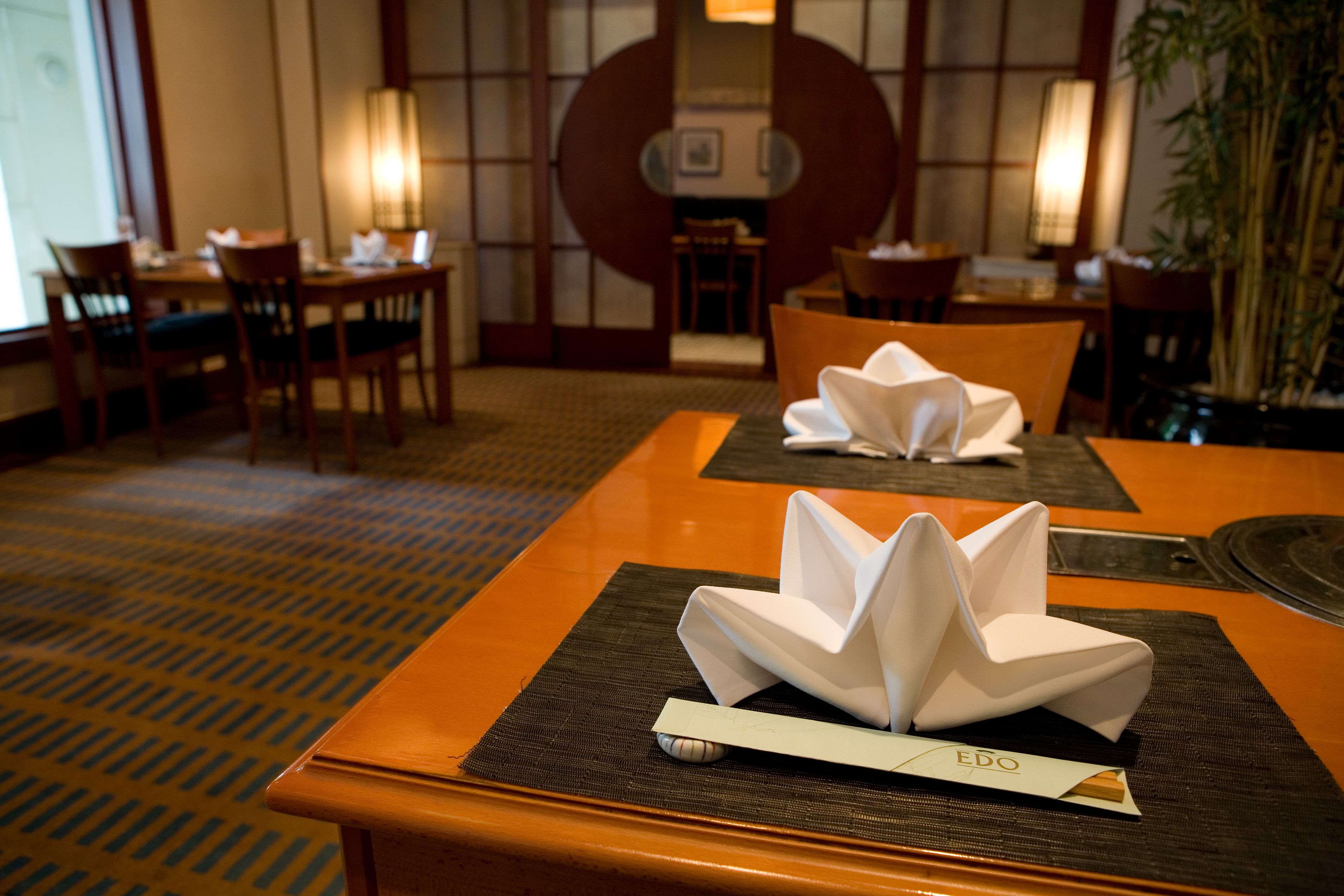 A dining area with tables set for two, featuring a traditional Japanese aesthetic with tatami mats and a low table.