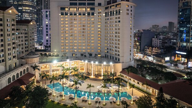 Un hotel con piscina, varios pisos y un logo rojo característico en la parte superior.