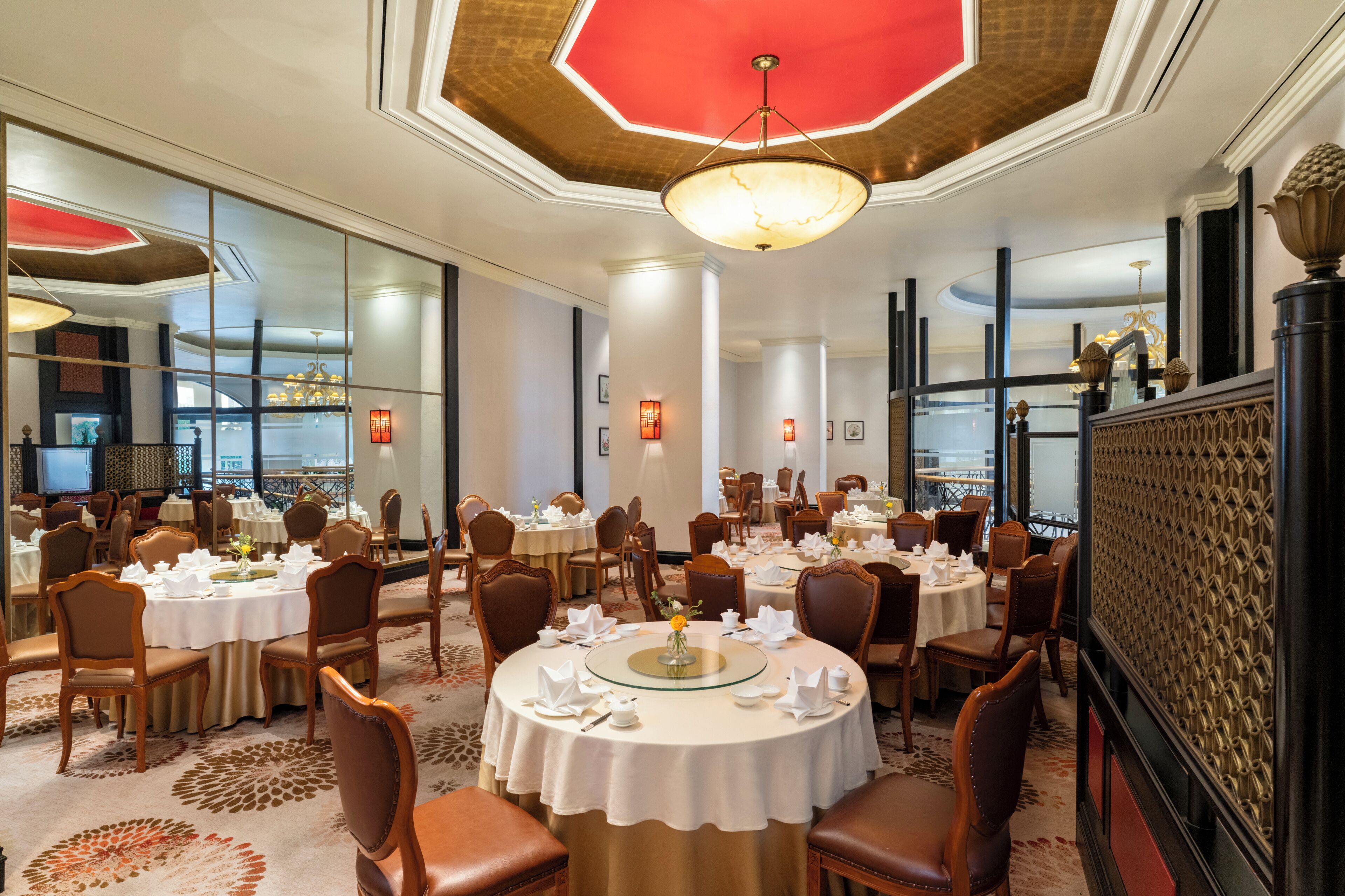 A hotel dining area with round tables, chairs, and a chandelier.